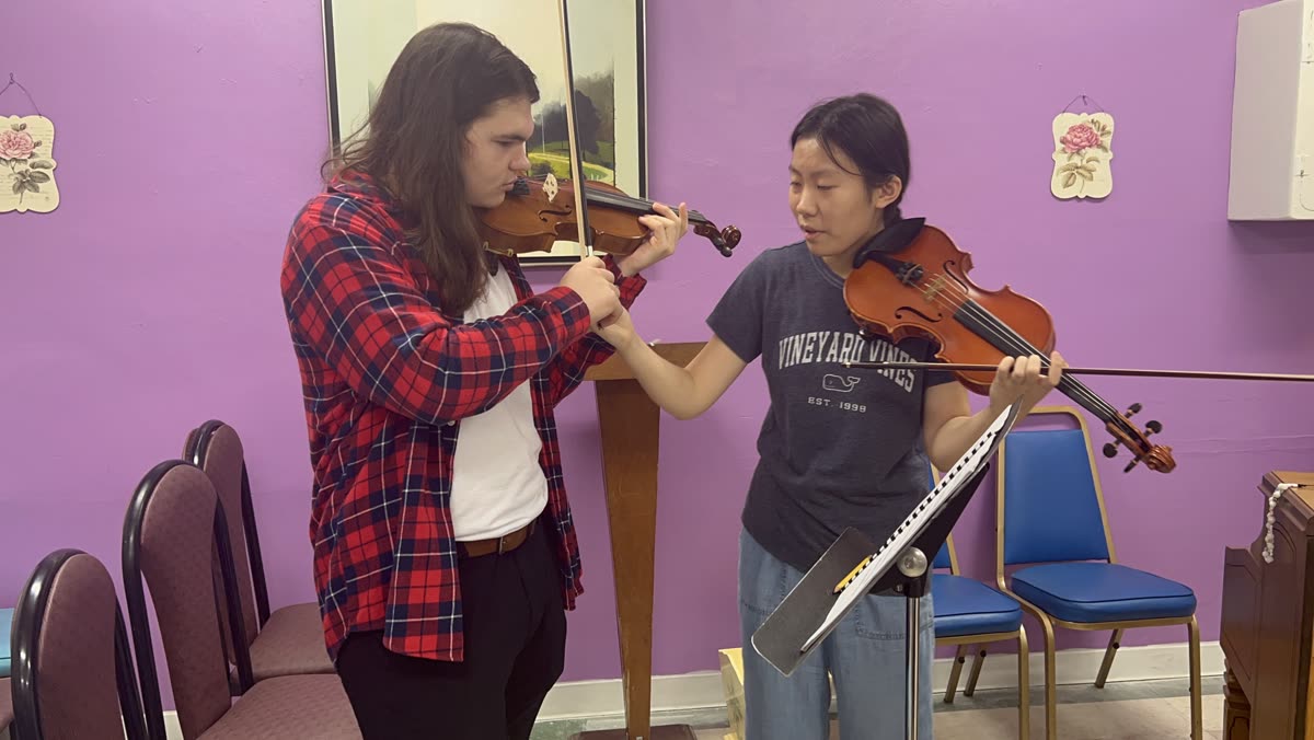 An OCAPEX mentor and a younger violinist practising side by side